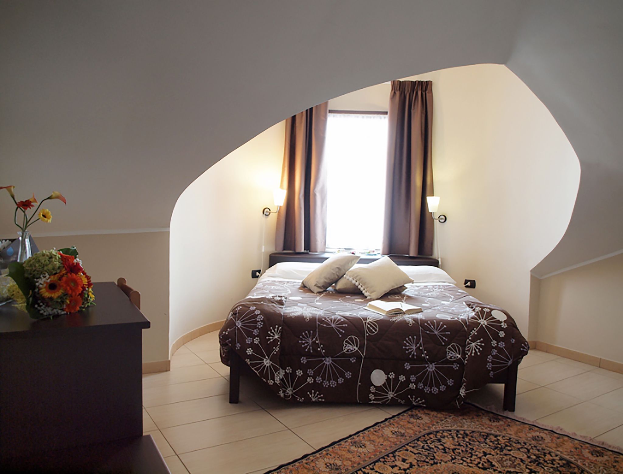 Une chambre à coucher avec un lit, un bureau et une fenêtre avec des rideaux.