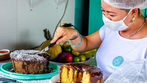 A person cutting a chocolate cake with a knife. - Pousada A Casa é Sua (Jijoca de Jericoacoara)