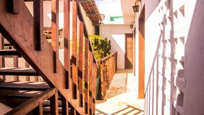 A narrow corridor with a wooden staircase on the left and a white gate on the right. - Pousada A Casa é Sua (Jijoca de Jericoacoara)
