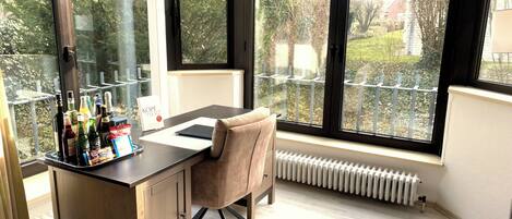 A room with a desk, chair, and large windows.