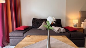 A modern living room with a sofa, a vase with a flower, and a wooden coffee table. - Haus Roseneck (Bad Bevensen)