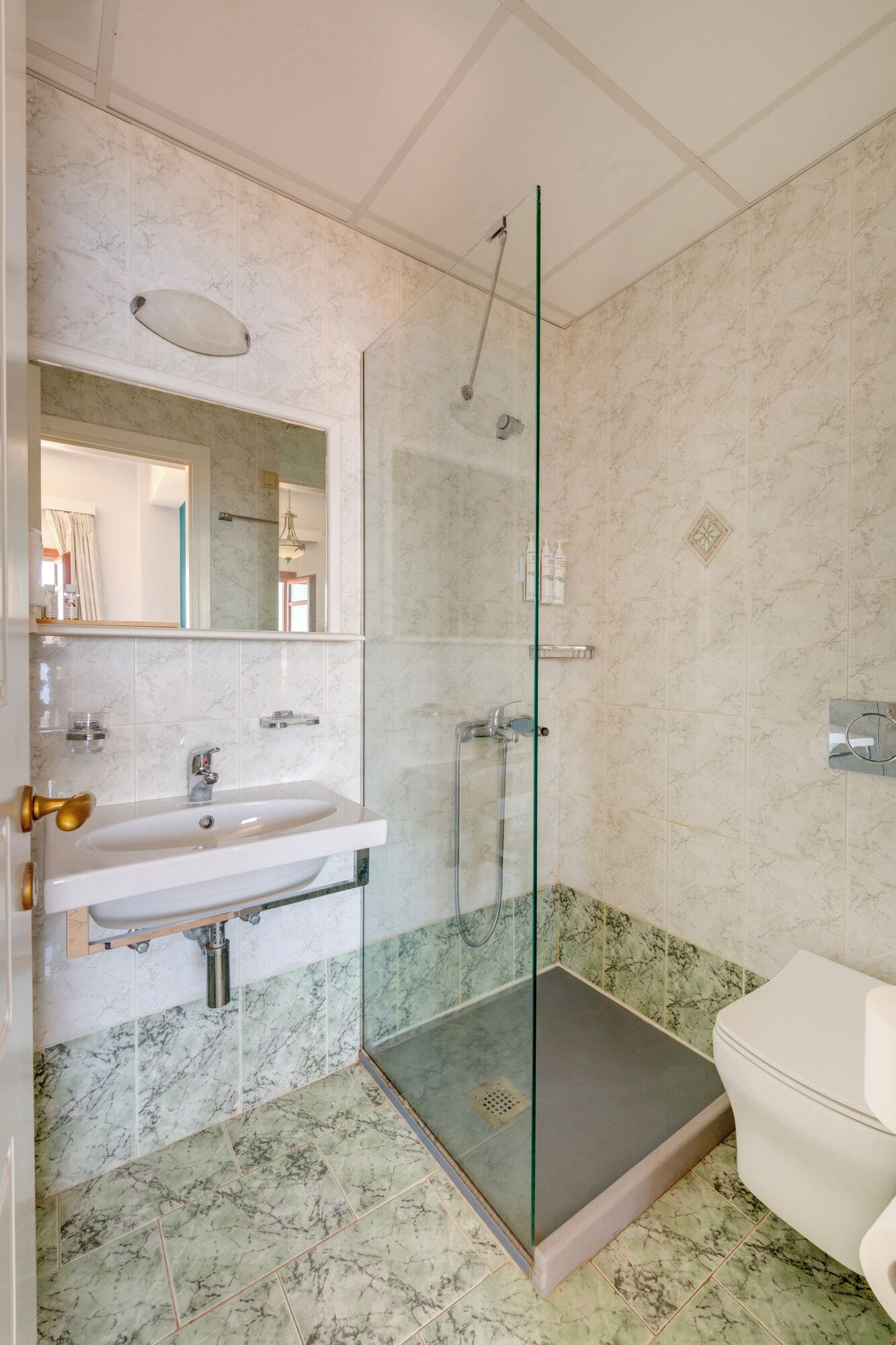 A bathroom with a glass-enclosed shower, a sink, and a toilet.