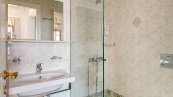 A bathroom with a glass-enclosed shower, a sink, and a toilet.