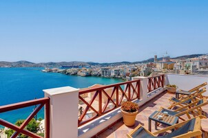 Una terraza con vistas a un pueblo costero, incluyendo edificios y un puerto.