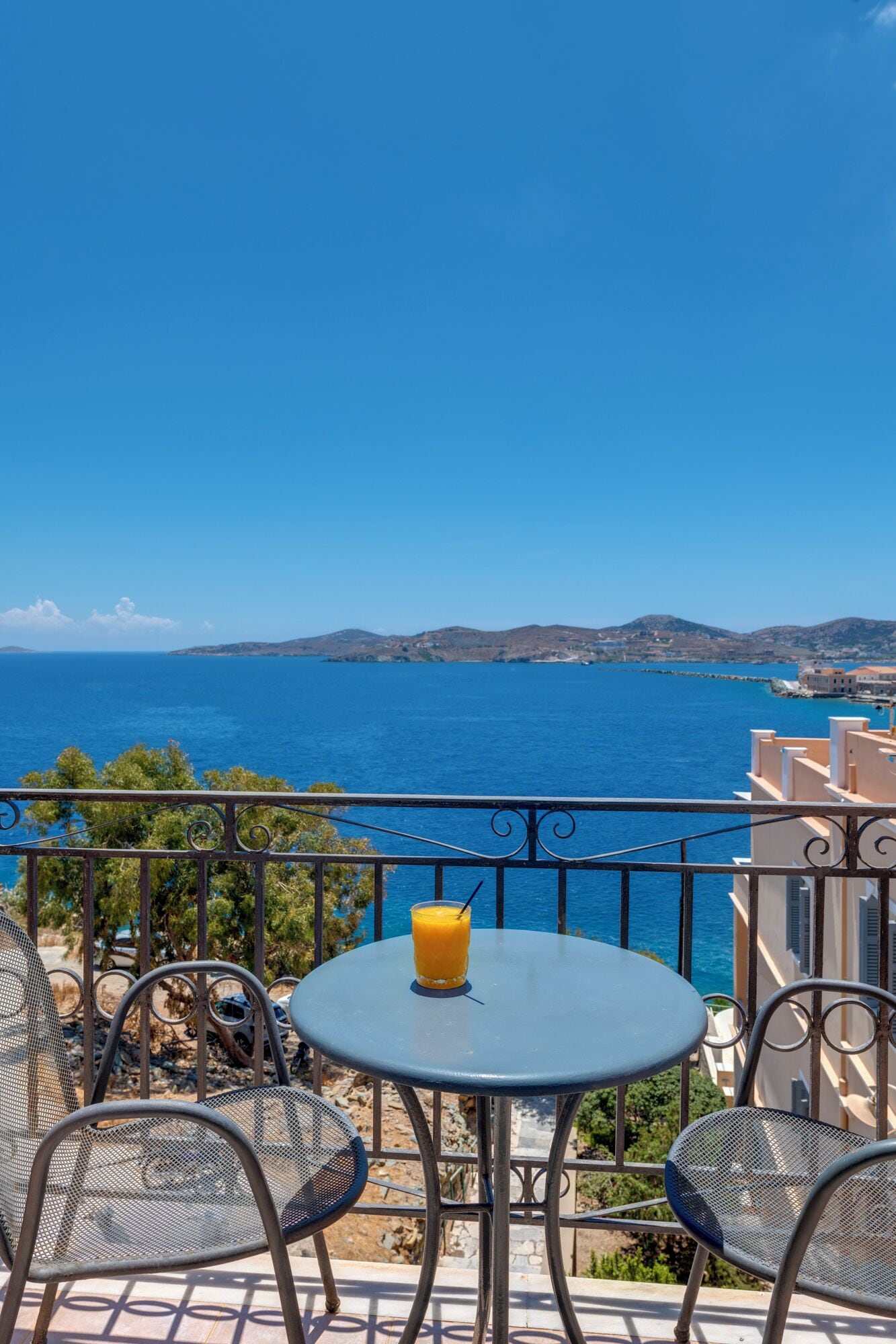 A balcony with a table and chairs overlooking a coastal view.