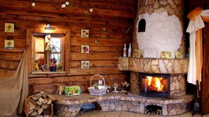 A cozy cabin interior with a stone fireplace, wooden walls, and a window with a view. - Centrum Wypoczynku Odys (Tresna)