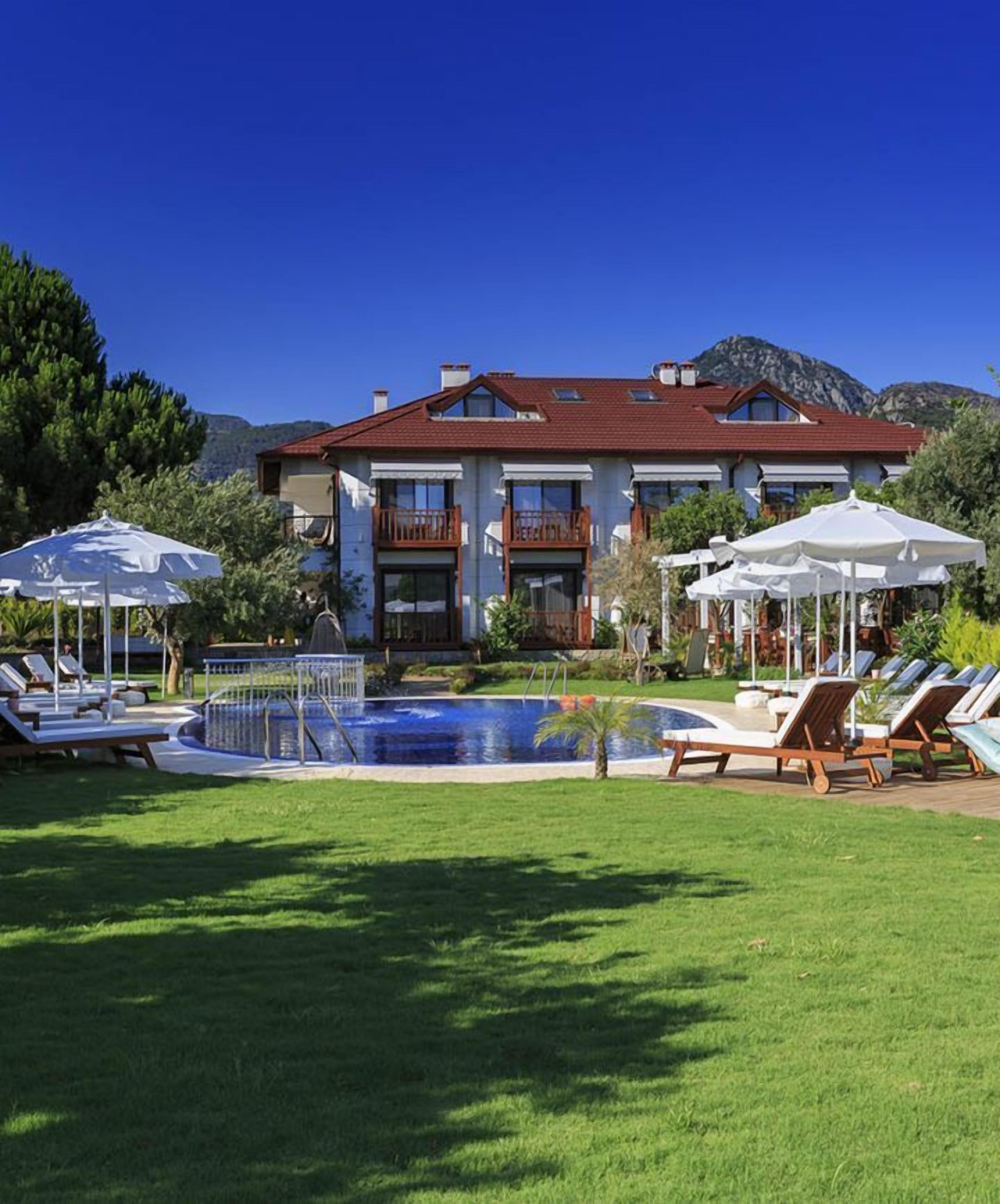 Una piscina al aire libre, sombrillas, sillones reclinables de piscina