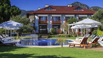 Una piscina al aire libre, sombrillas, sillones reclinables de piscina