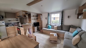 Un espacio habitable compacto con kitchenette, comedor, sofá y televisor.