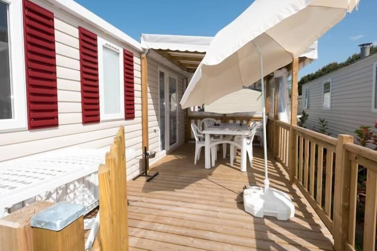 A wooden deck with a white umbrella, a table, and chairs.