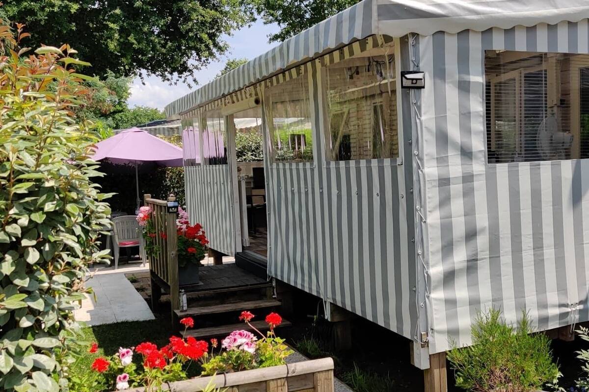 A striped, covered outdoor structure with a wooden deck and a purple umbrella.
