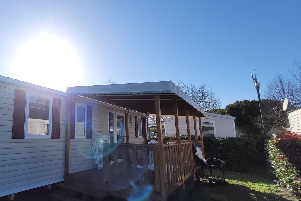 A mobile home with a covered porch and a small deck.