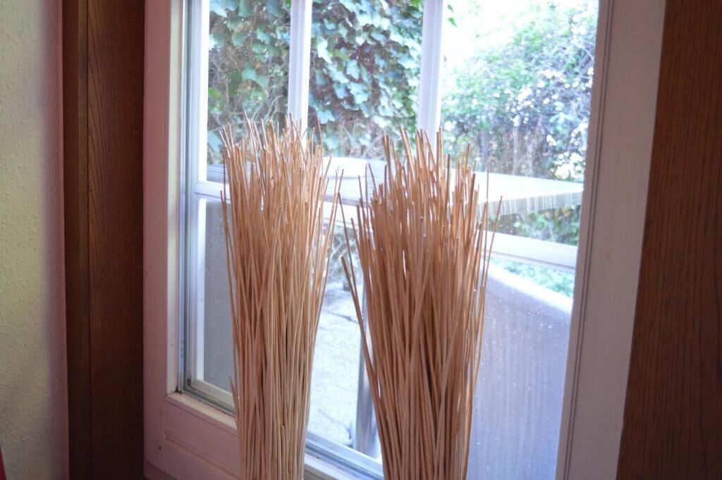 Een raam met daarboven twee hoge, slanke, beige voorwerpen, mogelijk decoratieve objecten.