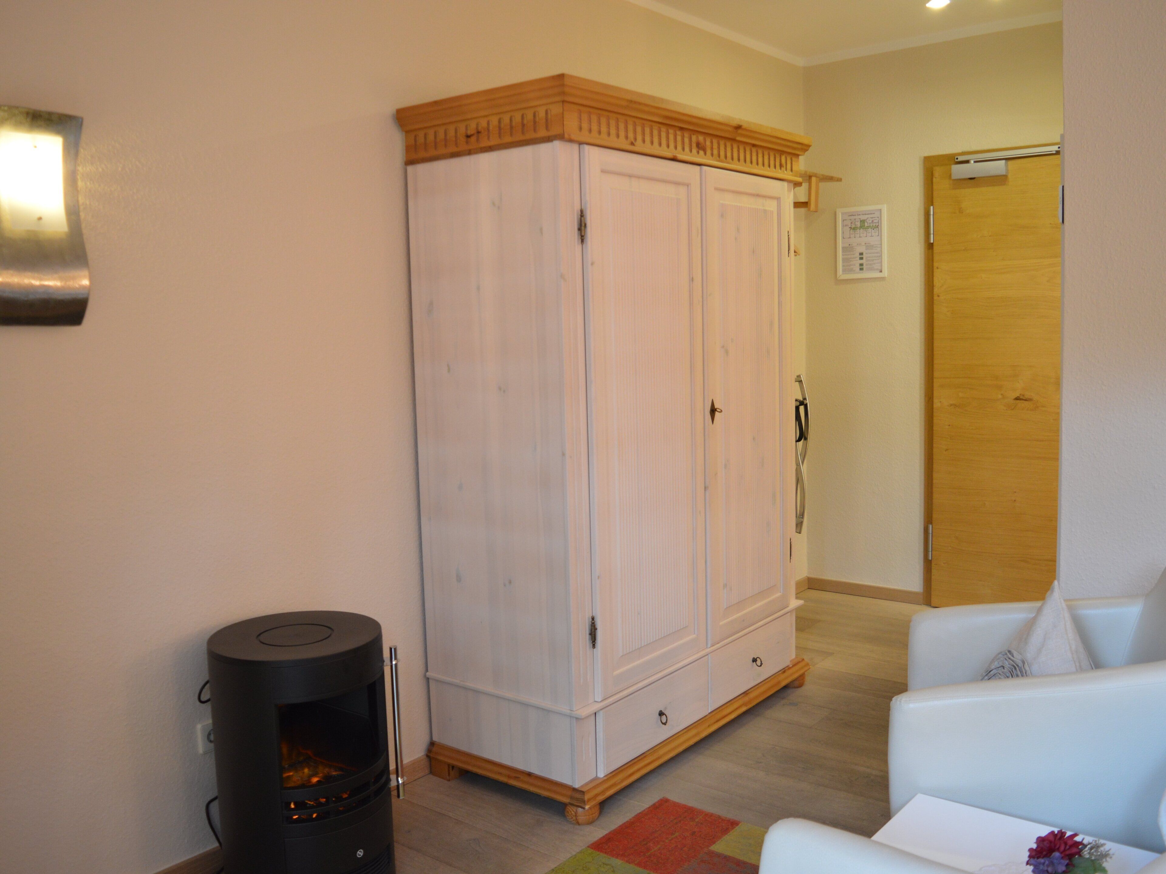 Una habitación con un armario blanco, un sofá blanco y un calefactor negro.