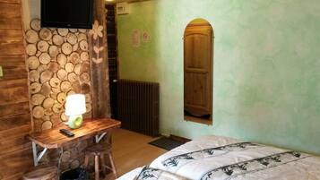 Une pièce avec un bureau en bois, une lampe, un lit recouvert d’une couvre-lit à motifs et une porte en bois.