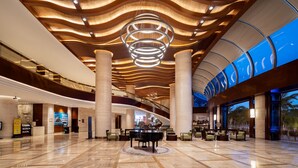 A spacious lobby with a grand piano, high ceilings with wooden paneling, and a large circular light fixture. - Grand Soluxe Hotel And Resort Sanya (Sanya)