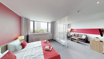Una habitació d'hotel amb un llit, un sofà, una taula de treball i una finestra gran.