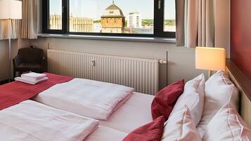 Habitación de hotel con dos camas, vista a un edificio con cúpula, una silla y una lámpara.