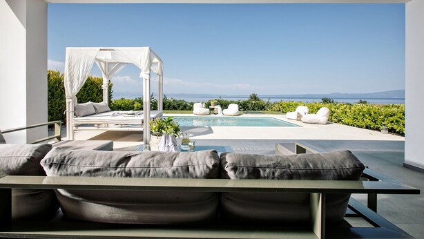 A modern outdoor lounge area with a pool, a canopy bed, and a view of the sea. - Bellevue Villas (Kassandra)