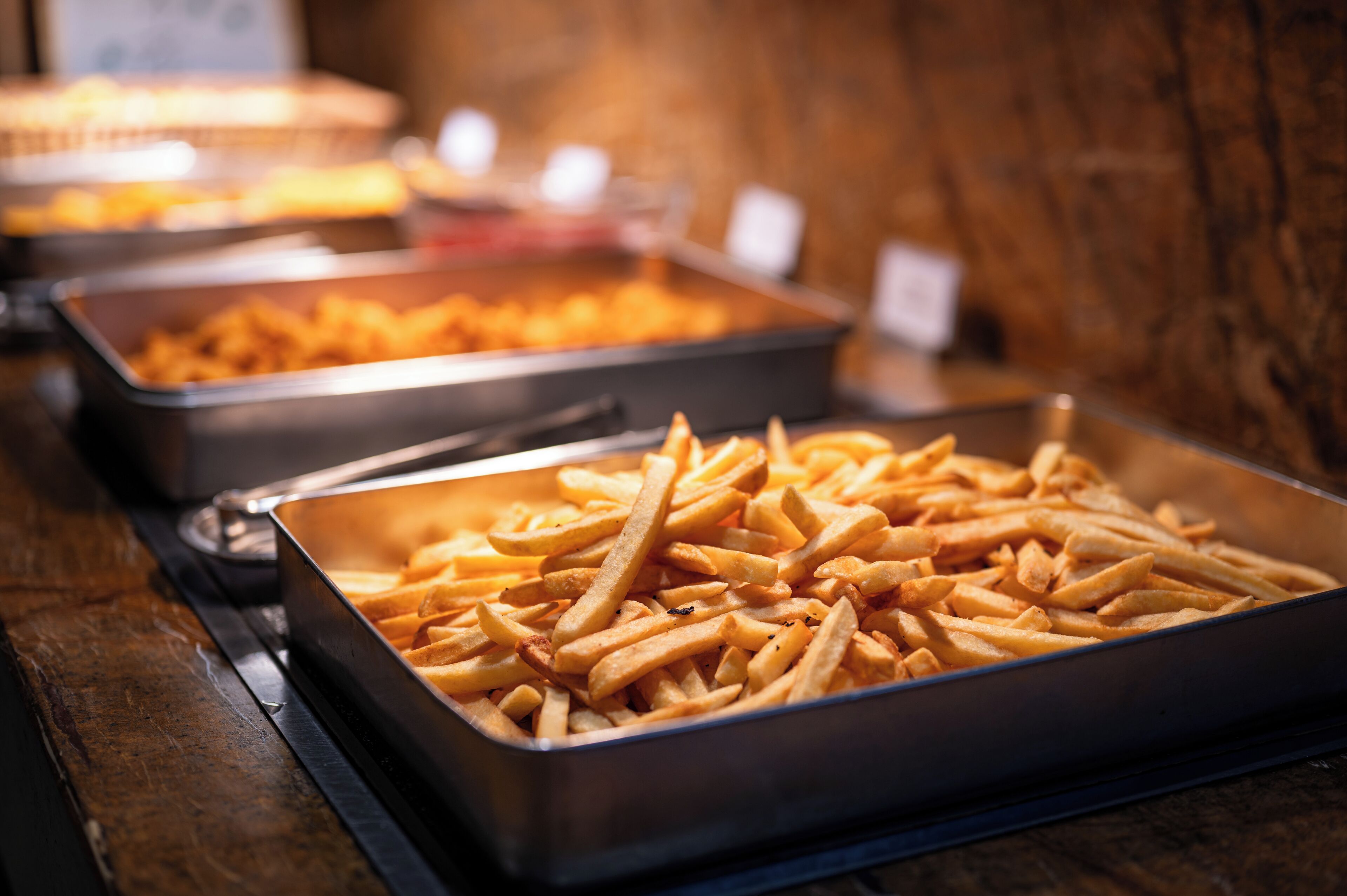 Un bufé con bandejas de papas fritas.