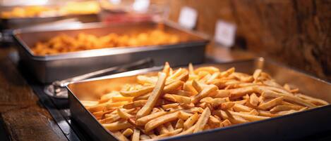 Un bufé con bandejas de papas fritas.