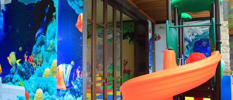 A children's play area with a slide and an aquarium wall.