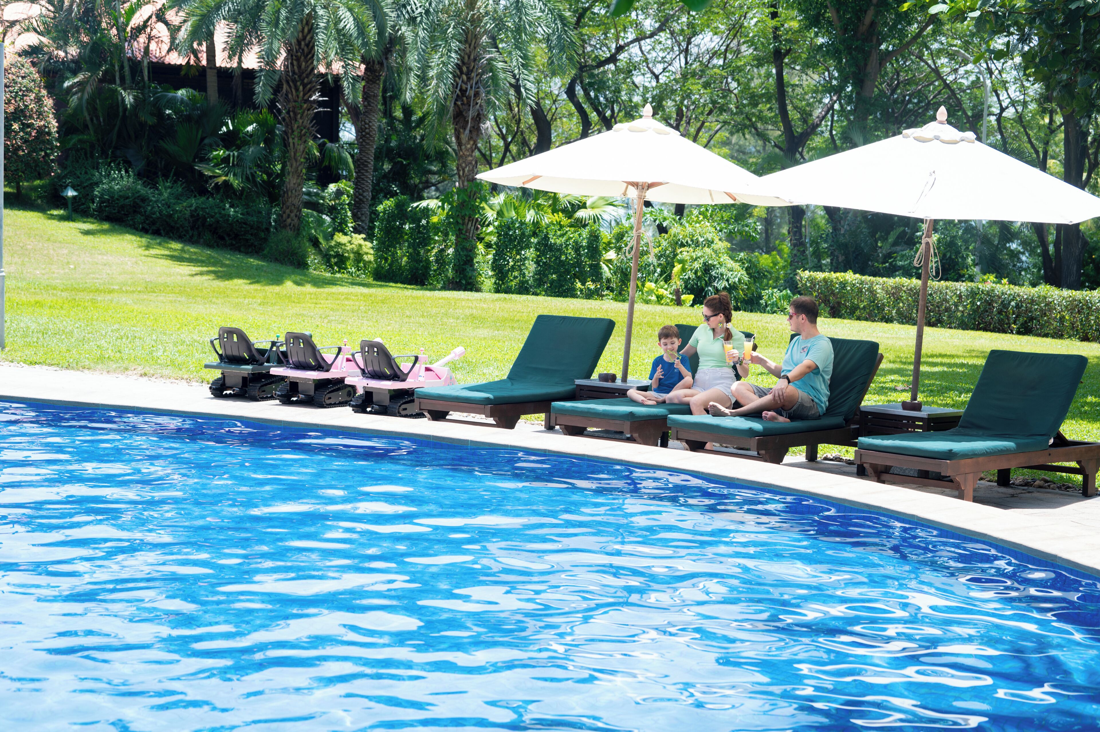 Una piscina con lettini e ombrelloni, immersa nel verde.