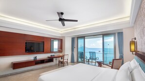 Une chambre d’hôtel équipée d’un lit, d’une télévision, d’un bureau et d’un balcon avec vue sur la mer.