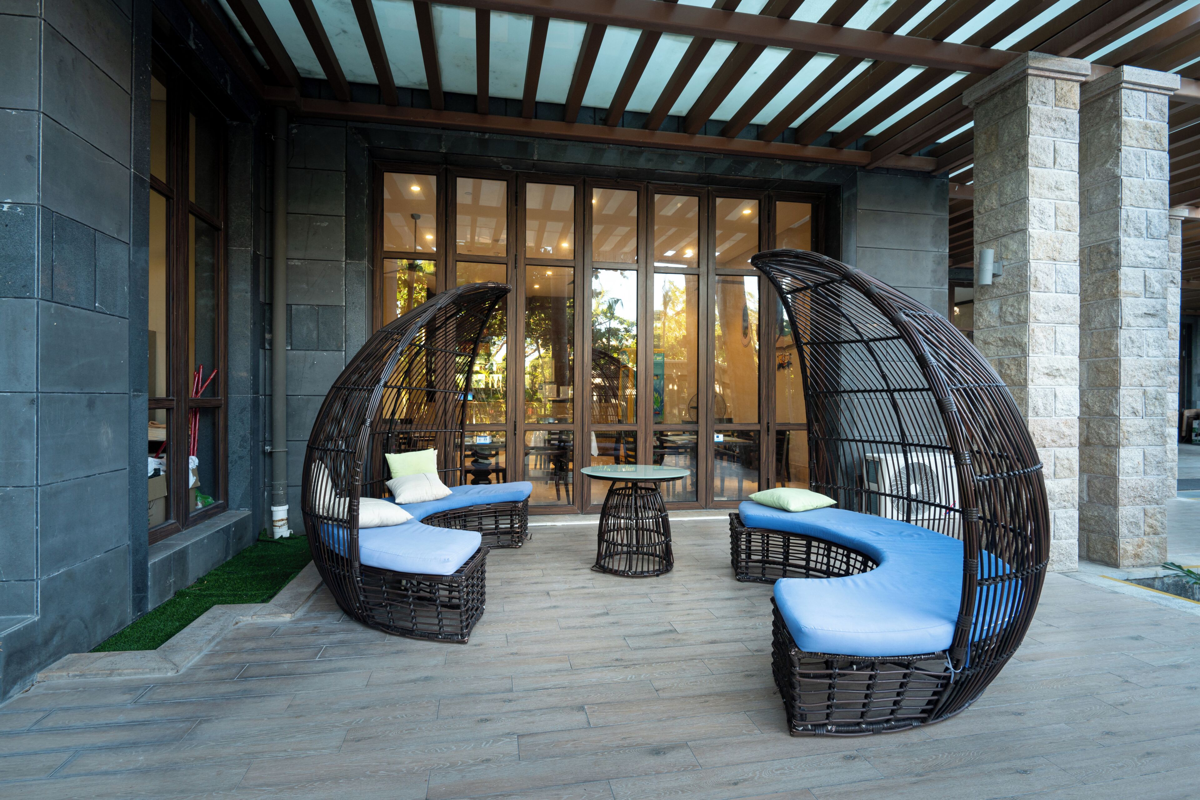 Un espacio de estar al aire libre cubierto, con sillas de mimbre y una mesa.