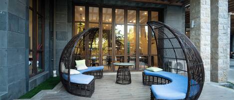 Un espacio de estar al aire libre cubierto, con sillas de mimbre y una mesa.