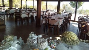 A restaurant with multiple tables set for dining, large windows, and a view of the outdoors. - Agriturismo San Fele (Cerchiara di Calabria)