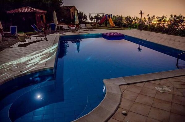 A swimming pool with a slide and lounge chairs.