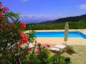 A pool area with a view of the countryside, a lounge chair, and a table.