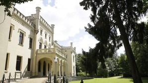 A large, historic building with a symmetrical facade, arched windows, and a central entrance.