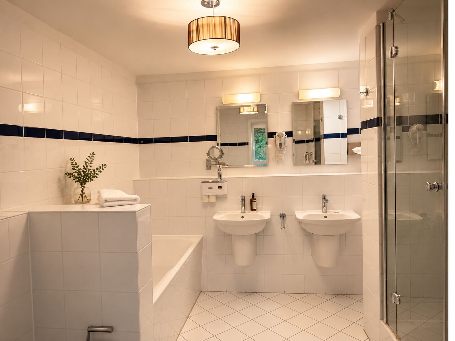 Een moderne badkamer met twee wastafels, een bad en een douchecabine met glazen wanden.