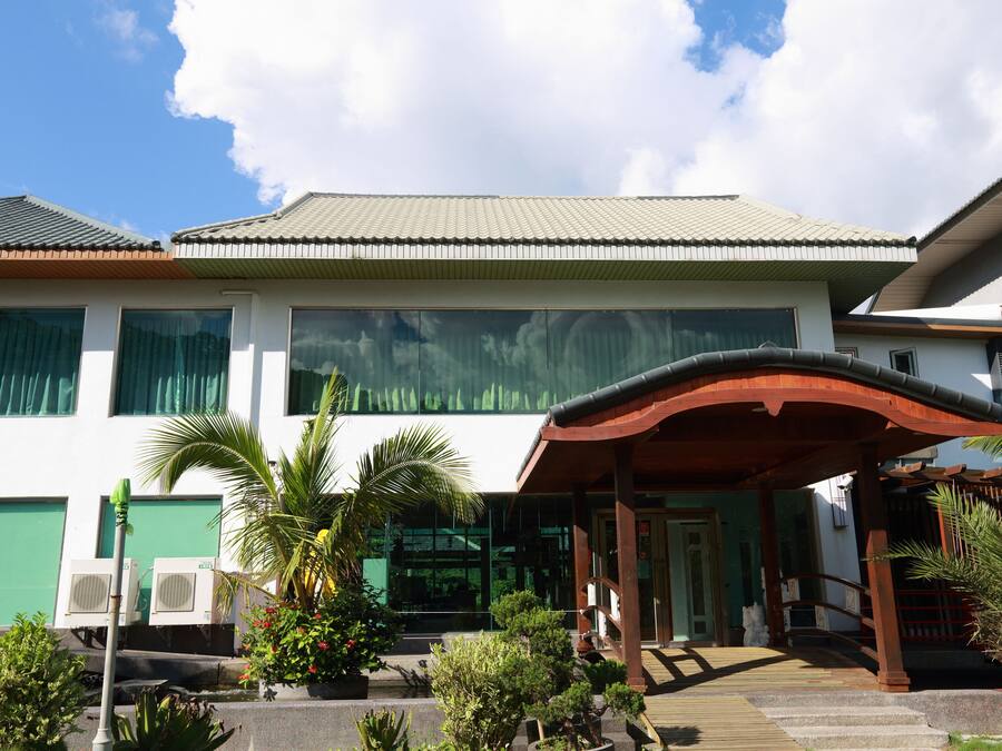 A two-story building with a covered entrance, large windows, and a tiled roof.