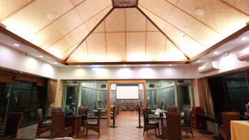 A conference room with a high ceiling, multiple tables, and chairs arranged for meetings.