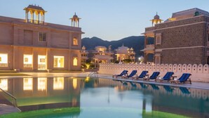 A pool area with lounge chairs and a building with traditional architecture. - Bhanwar Singh Palace (Pushkar)