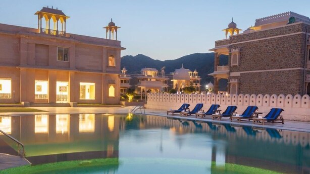 A pool area with lounge chairs and a building with traditional architecture.