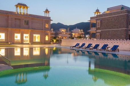 A pool area with lounge chairs and a building with traditional architecture.
