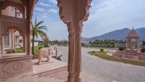 A courtyard with a large elephant statue, a gazebo, and a mountain in the background.