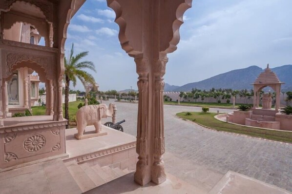 A courtyard with a large elephant statue, a gazebo, and a mountain in the background. - Bhanwar Singh Palace (Pushkar)