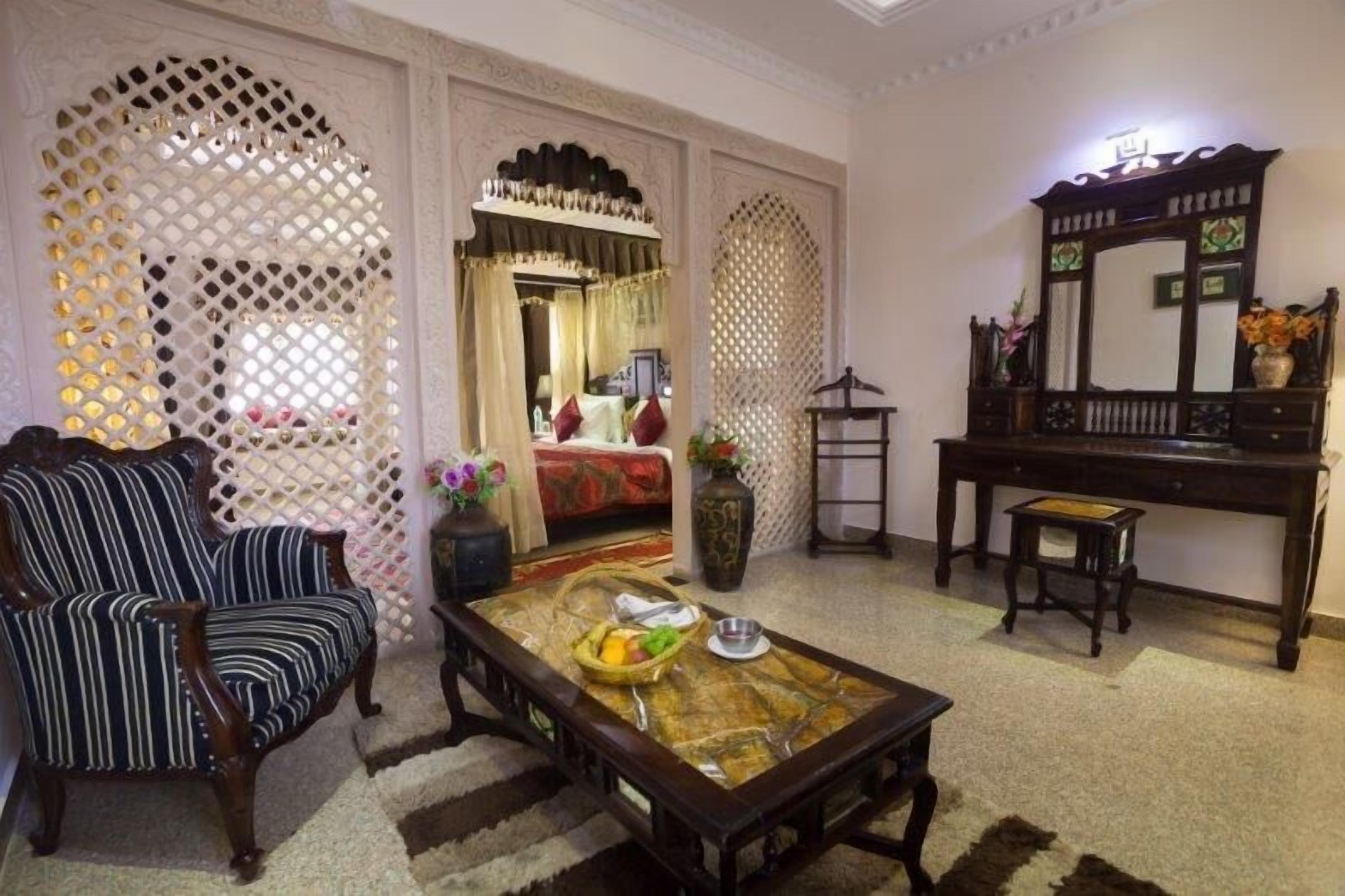 A traditional room with a sofa, a coffee table with fruits, a mirror, and decorative screens.