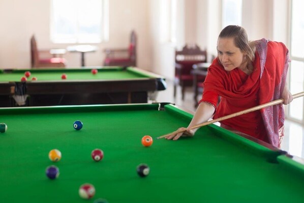 A person playing pool in a room with multiple tables. - Bhanwar Singh Palace (Pushkar)
