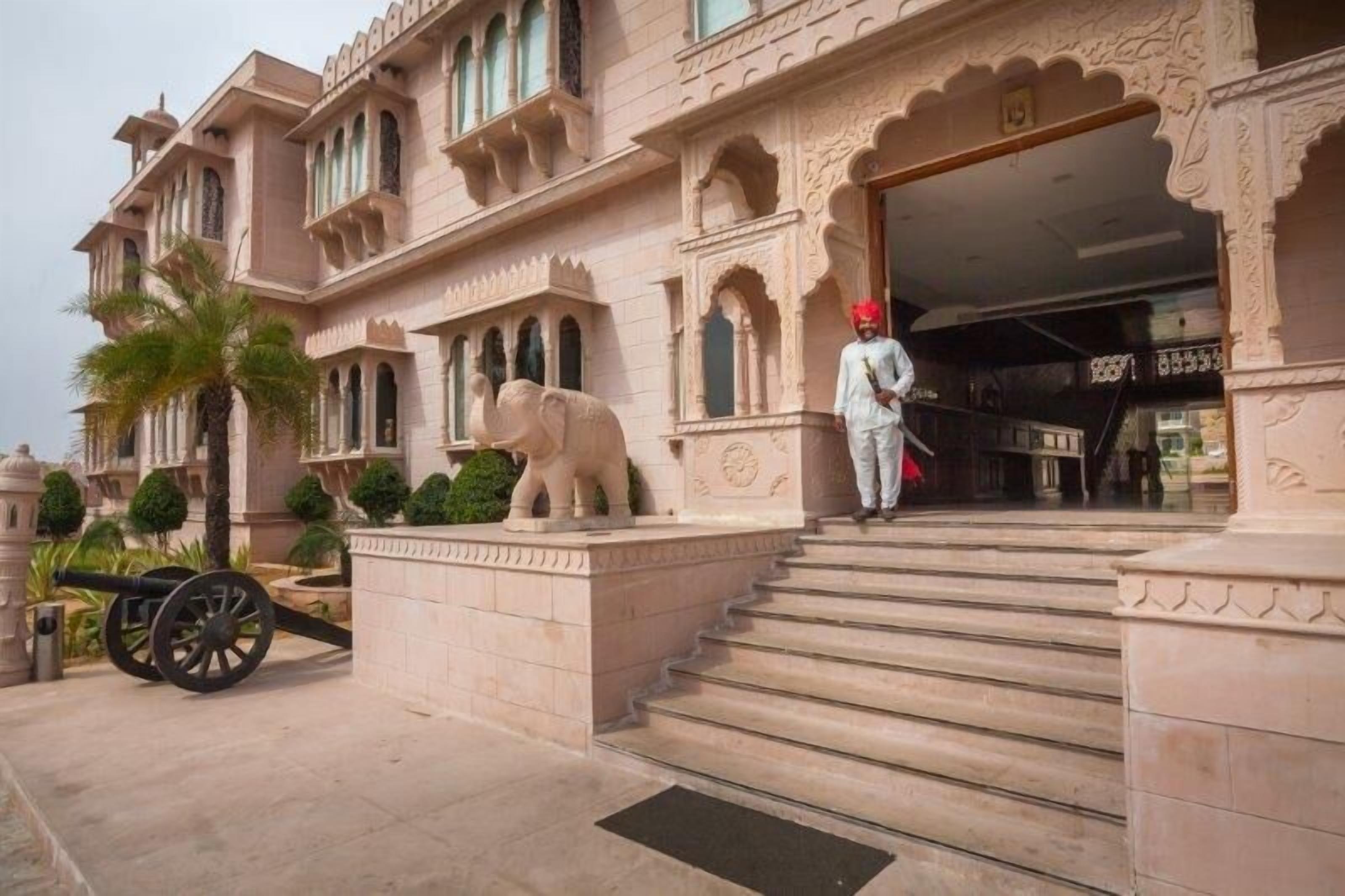 A grand entrance with a statue of an elephant, steps leading up to the door, and a guard standing at the entrance.
