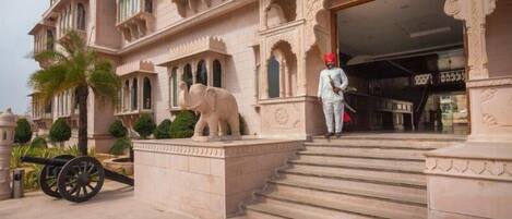 A grand entrance with a statue of an elephant, steps leading up to the door, and a guard standing at the entrance.