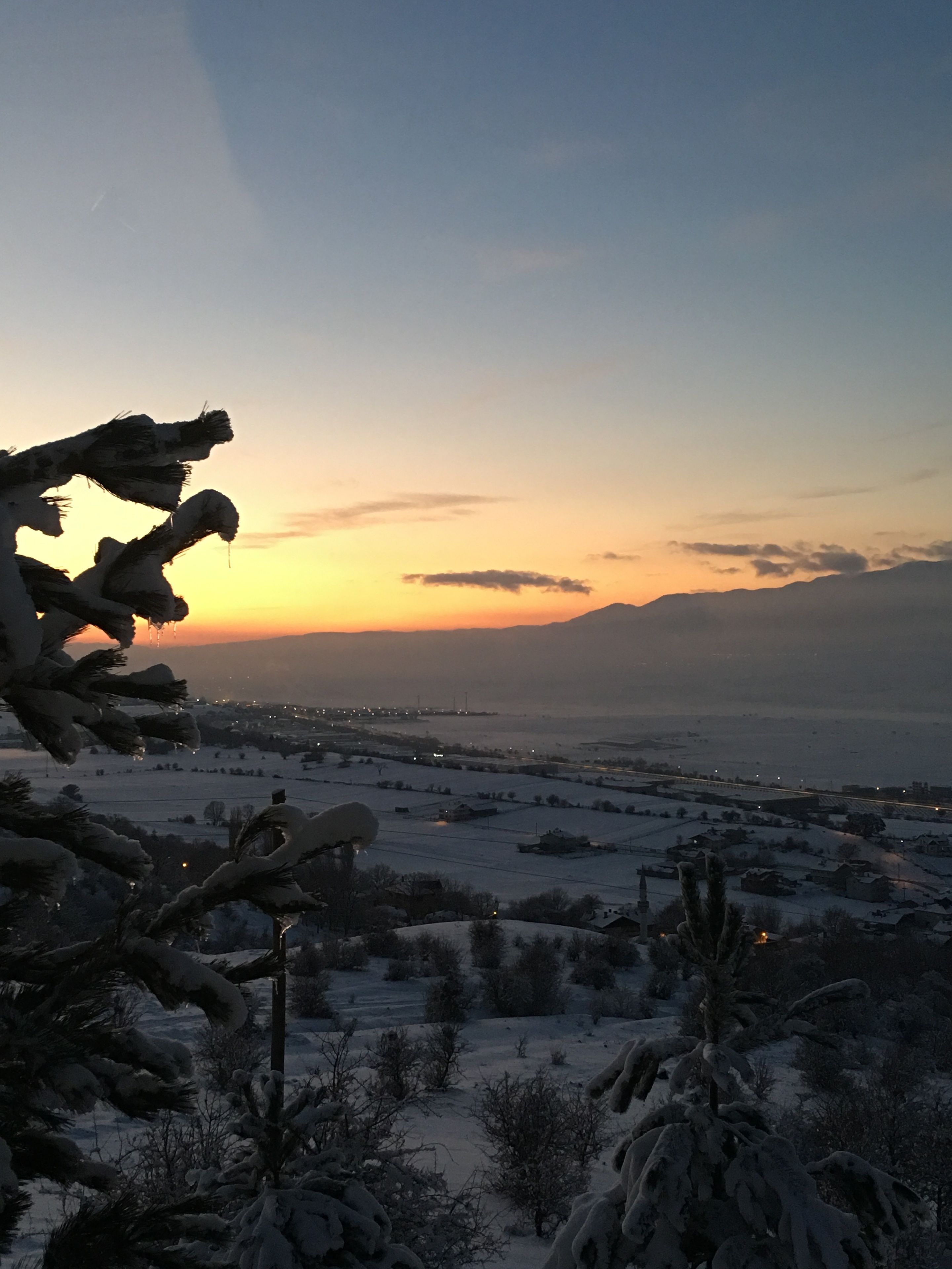 A snowy landscape with a sunset in the background.