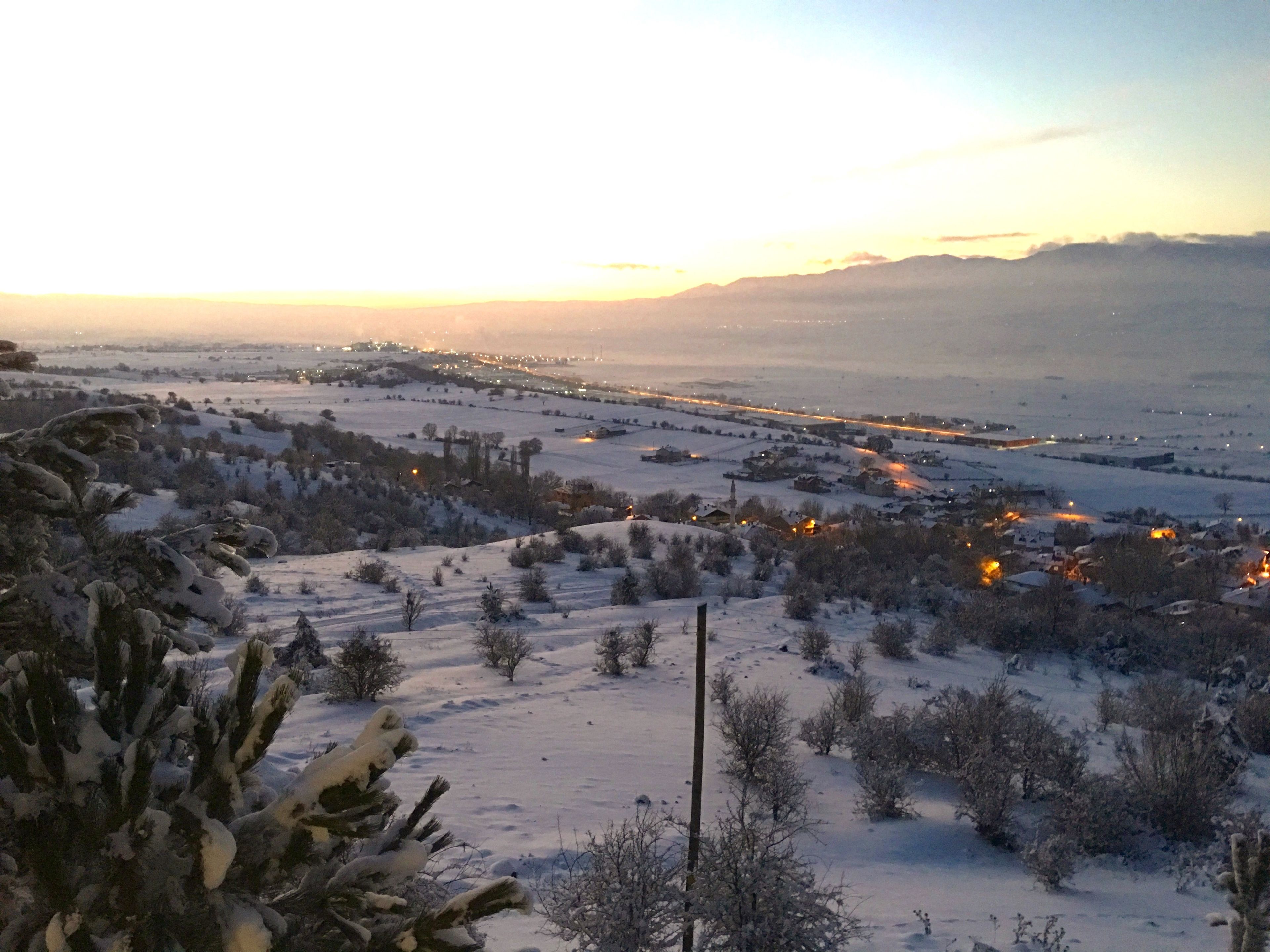 A snowy landscape with a distant view of a town and a clear sky.