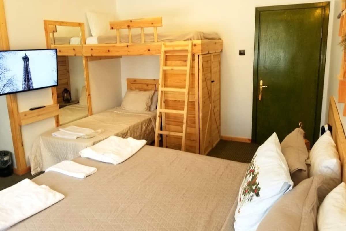 Ein Zimmer mit Etagenbetten, einem Fernseher, einer Tür und ordentlich gefalteten Handtüchern.