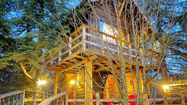 A wooden cabin with a wooden deck and a staircase leading to the entrance.